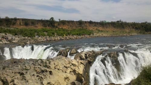 Scenic view of waterfall in forest against sky