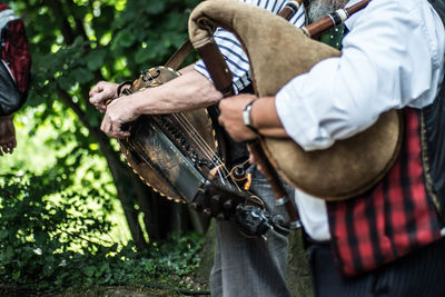 Midsection of men playing bagpipes outdoors