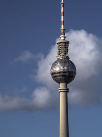 Low angle view of communications tower against cloudy sky