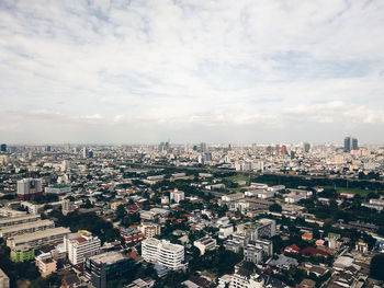 High angle view of city buildings against cloudy sky