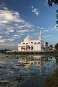 Reflection of building in lake against cloudy sky