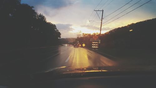 Cars on road against sky during sunset