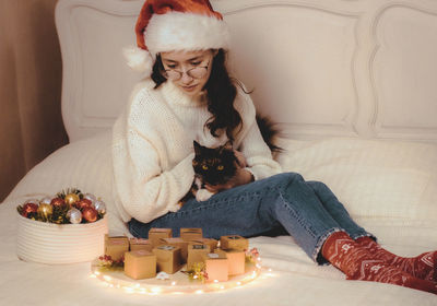 Girl with a cat and an advent calendar on the bed.