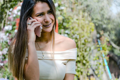 Smiling young woman talking on smart phone outdoors