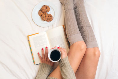High angle view of woman with coffee cup on book