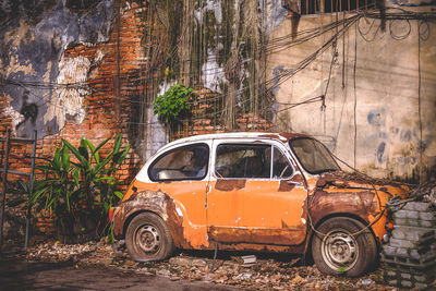 Abandoned car on street against building