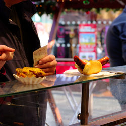 Midsection of man at stall counter buying hotdog