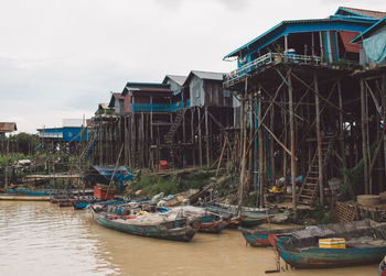 Boats moored in canal by buildings against sky