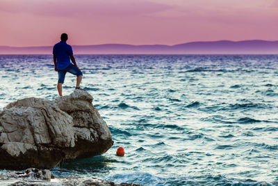 Rear view of man looking at sea against sky