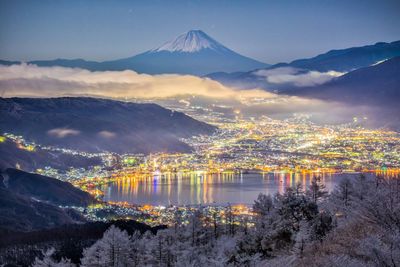 Scenic view of lake by mountains against sky during winter