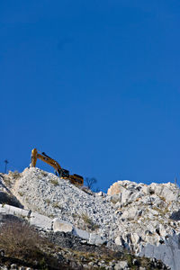 Low angle view of rocks against clear blue sky