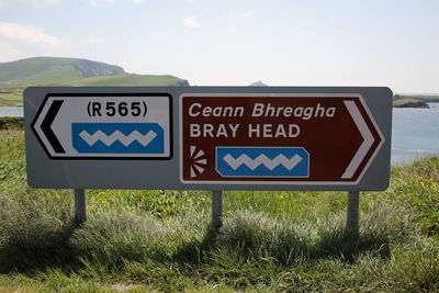 Information sign on field against sky