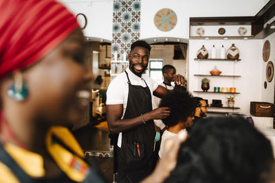 Smiling male barber talking with female coworker in hair salon