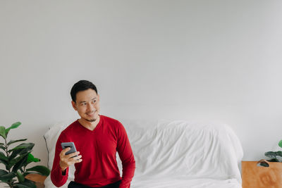 Portrait of young man with arms crossed against white background