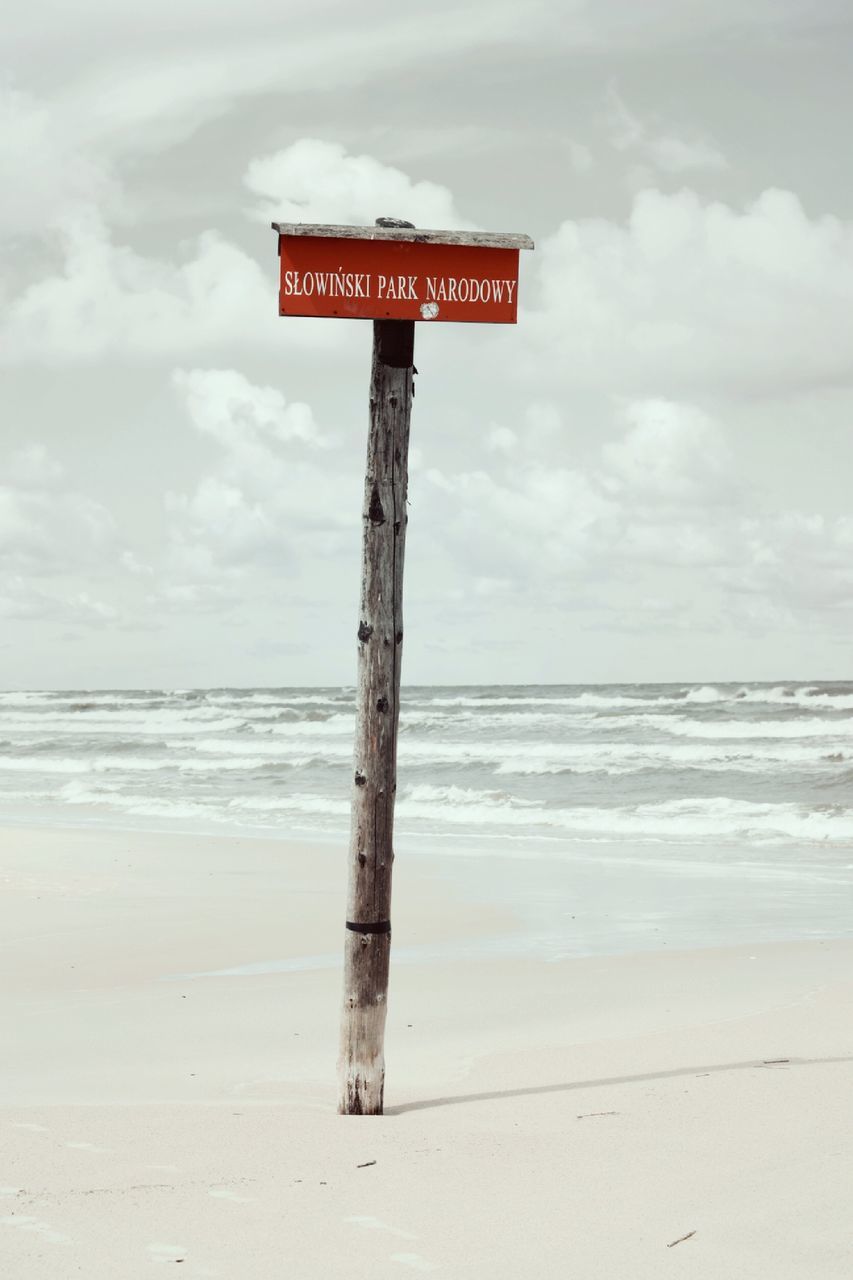 communication, sky, water, land, horizon, text, sea, beach, horizon over water, sign, cloud - sky, western script, scenics - nature, beauty in nature, warning sign, nature, day, motion, no people, guidance, outdoors, wooden post