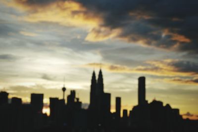 Silhouette of cityscape against cloudy sky
