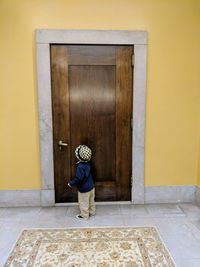 Rear view of man standing against closed door