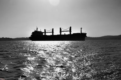 Silhouette people on boat in sea against sky