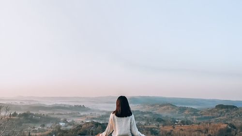 Rear view of woman looking at mountain against sky