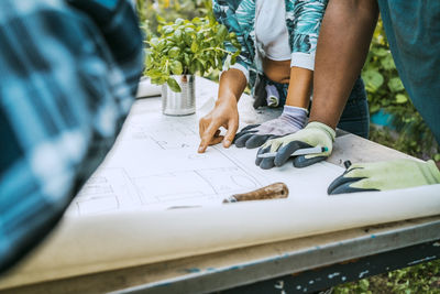 Cropped image of male and female volunteers pointing at drawing over table in farm