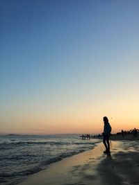 Silhouette man walking on beach against clear sky