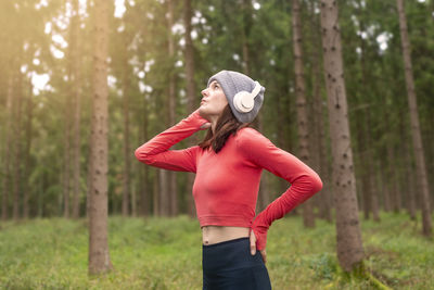 Sporty woman runner training outdoors in a forest, listening to music with headphones