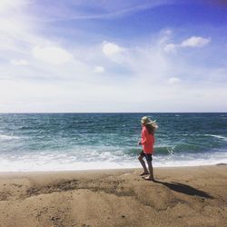 Full length of girl walking at beach against sky