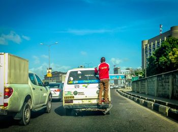 Man standing on street in city against sky