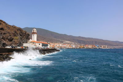 Sea by buildings against clear blue sky