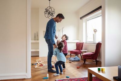 Playful children talking to father while standing at home