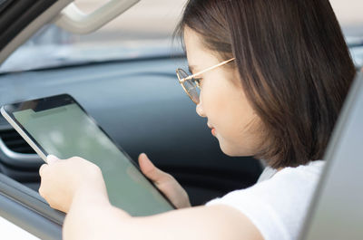 Portrait of young woman using mobile phone in car