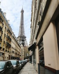 Low angle view of eiffel tower in city against cloudy sky