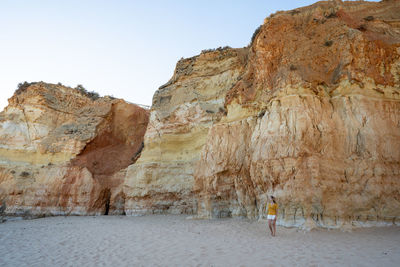 Rear view of person on rock against sky