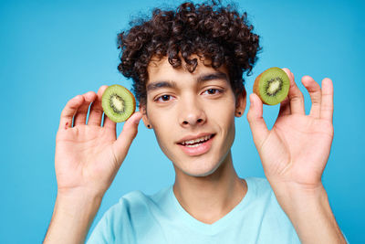 Portrait of smiling man holding fruit against blue background