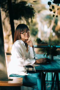 Young woman using phone while sitting on table