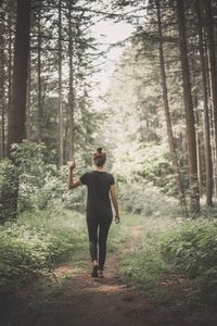 Full length of man standing amidst trees in forest