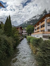 Houses by river against sky