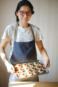 Portrait of woman showing food in tray at home