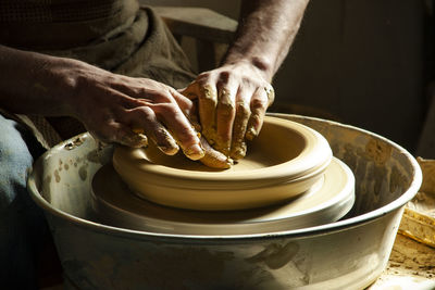 Hands of a potter working with clay in natural light at a workshop