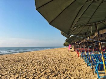 Umbrellas hanging on beach against clear sky