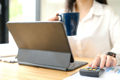 Midsection of woman using laptop at table