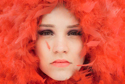 Close-up portrait of young woman amidst red feathers