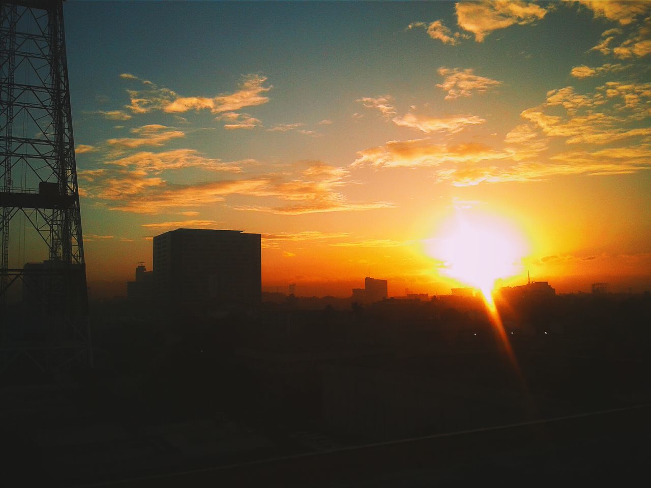 sunset, building exterior, silhouette, architecture, sun, built structure, sky, orange color, city, sunlight, cloud - sky, sunbeam, building, skyscraper, cityscape, cloud, lens flare, outdoors, no people, nature