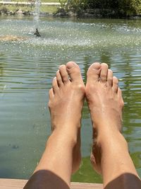 Low section of man relaxing on wet lake