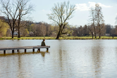 Little boy sitting outdoors, near to the lake and relaxing. water and sunny weather. 