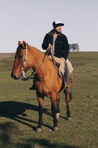 Man riding horse on land against clear sky