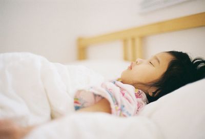 Side view of baby sleeping on bed at home