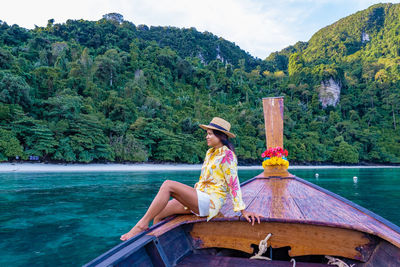 Rear view of man sitting on boat in sea