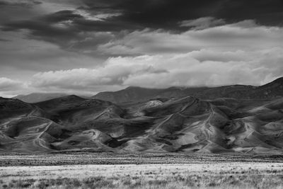 Scenic view of desert against cloudy sky