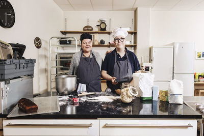 Portrait of bakers standing by kitchen counter